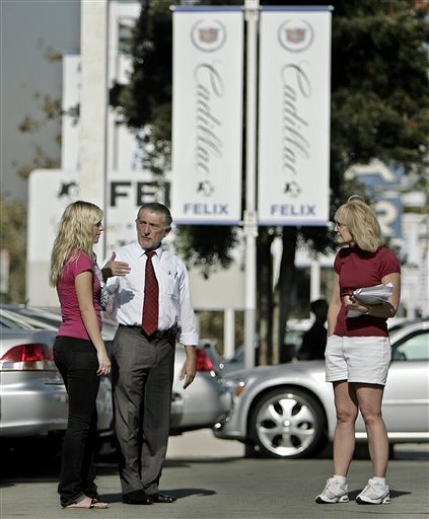 Chevrolet salesman Philip Jordan, center, assists Charlotte Olson, right, who's looking to buy a car for her 18-year-old daughter, Kari Olson, left, Wednesday, Nov. 12, 2008, in downtown Los Angeles. Treasury Secretary Henry Paulson called autos a "critical industry" Wednesday but said a $700 billion financial rescue program wasn't designed for them. The White House was noncommital, but said it was open to new ideas. (AP Photo/Ric Francis)