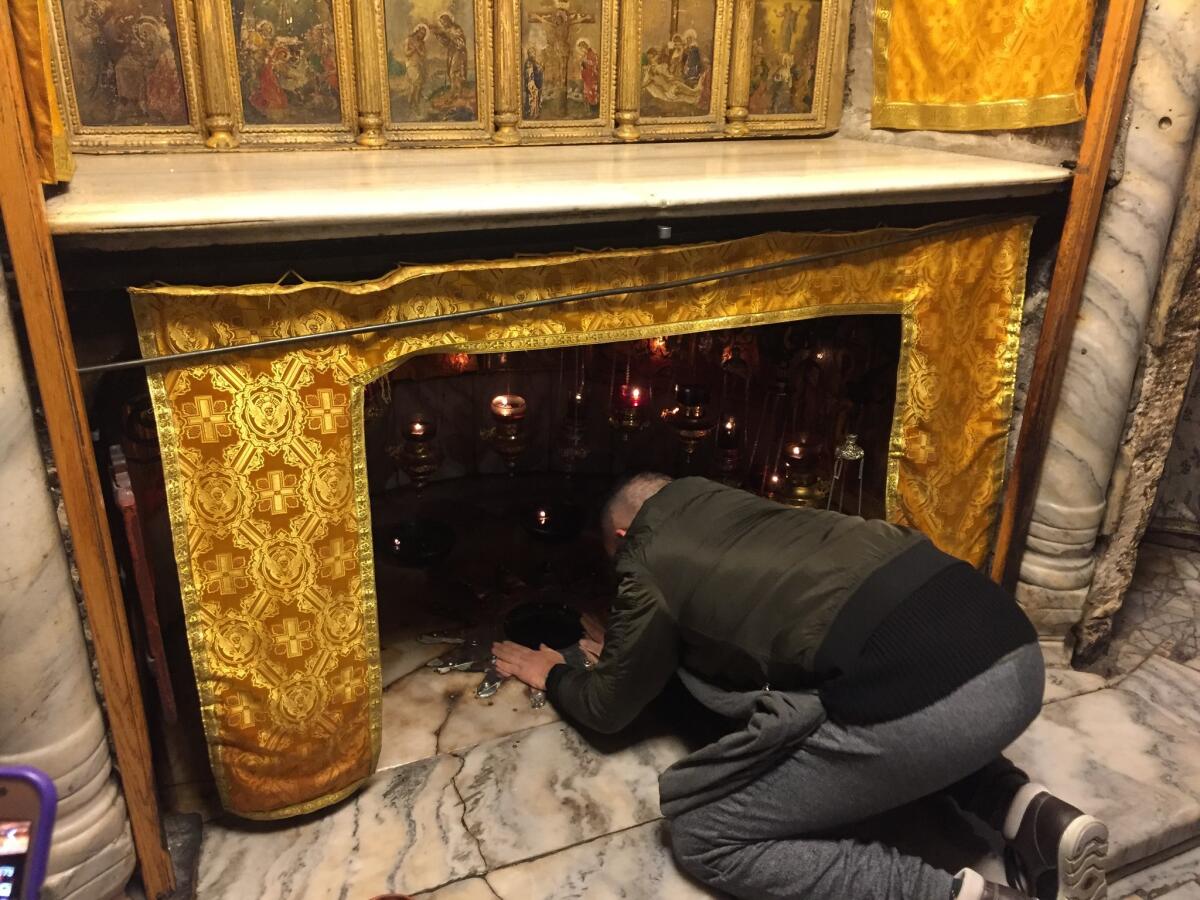 A man puts his hands on the Star of Bethlehem, which marks the site where Jesus is believed to have been born.