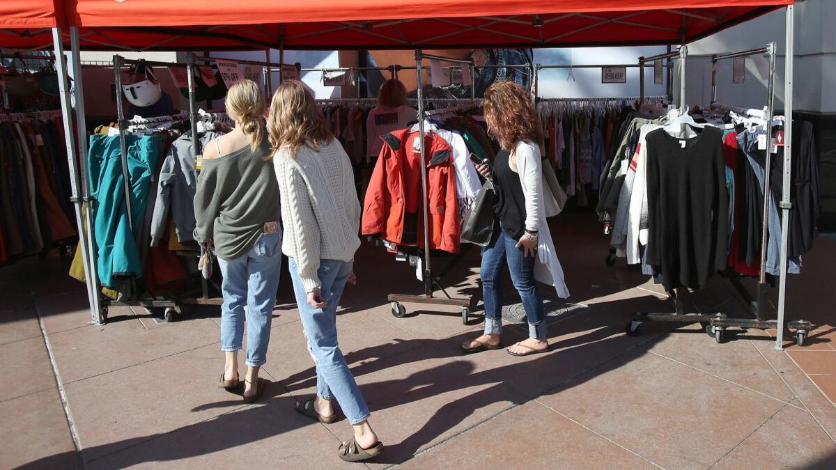 Shoppers walk among racks of Jack’s Surfboards merchandise in downtown Huntington Beach on Friday.