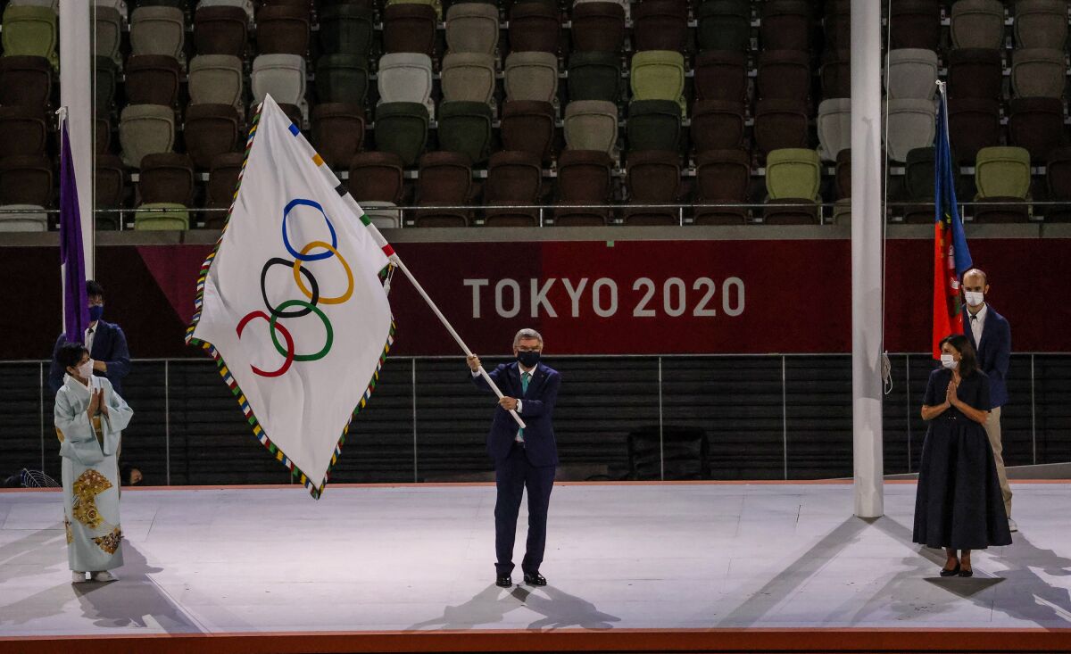 Thomas Bach, president of the International Olympic Committee, waves the Olympic flag.