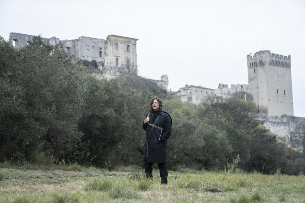 Un voyageur (Norman Reedus dans le rôle de Daryl) se promène dans la campagne près d'un château français 