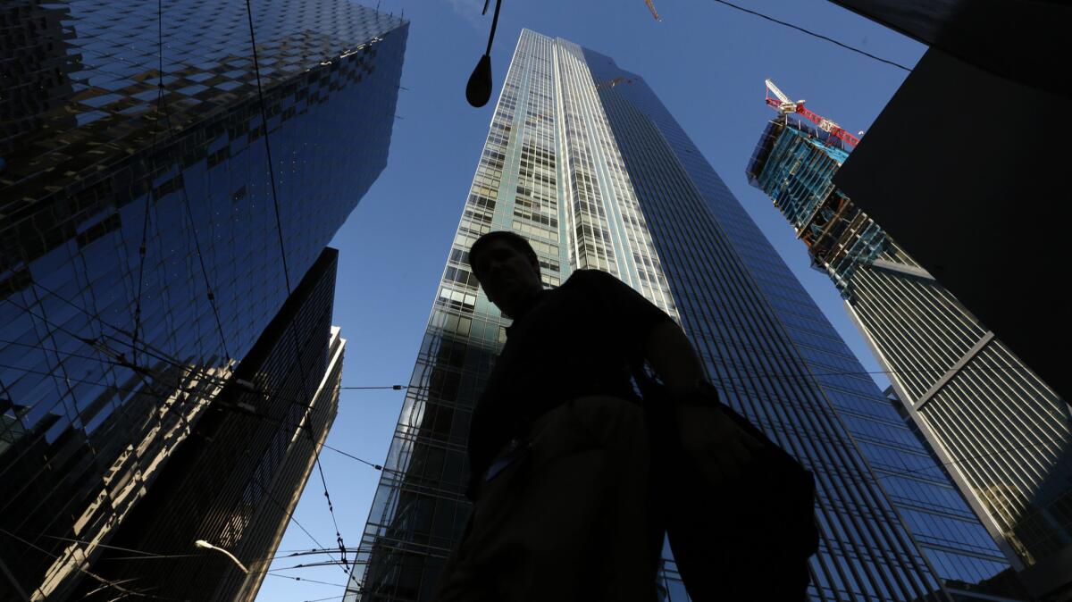 A pedestrian walks past the luxury Millennium Tower, a 58-story high-rise in San Francisco.