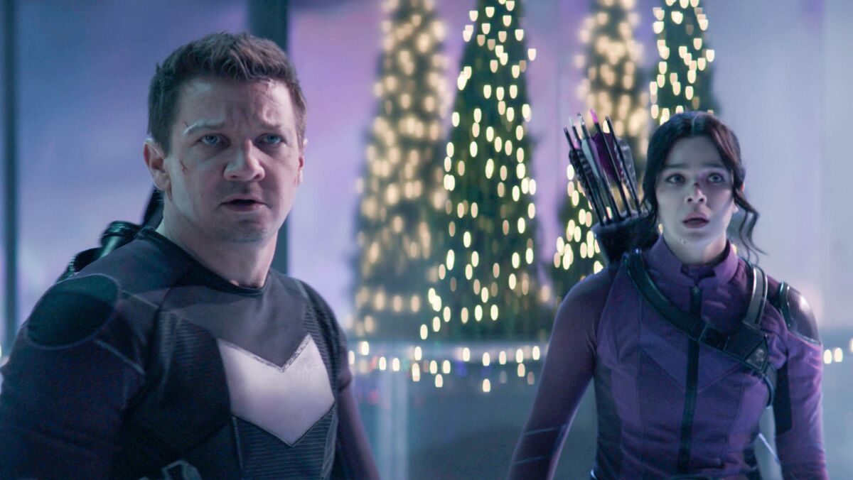 a man and a woman, each with a quiver of arrows, with festively lighted trees behind them