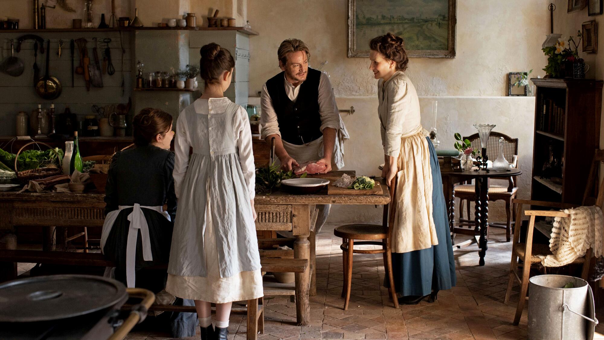 A woman and a man cook together in a kitchen, with helpers.