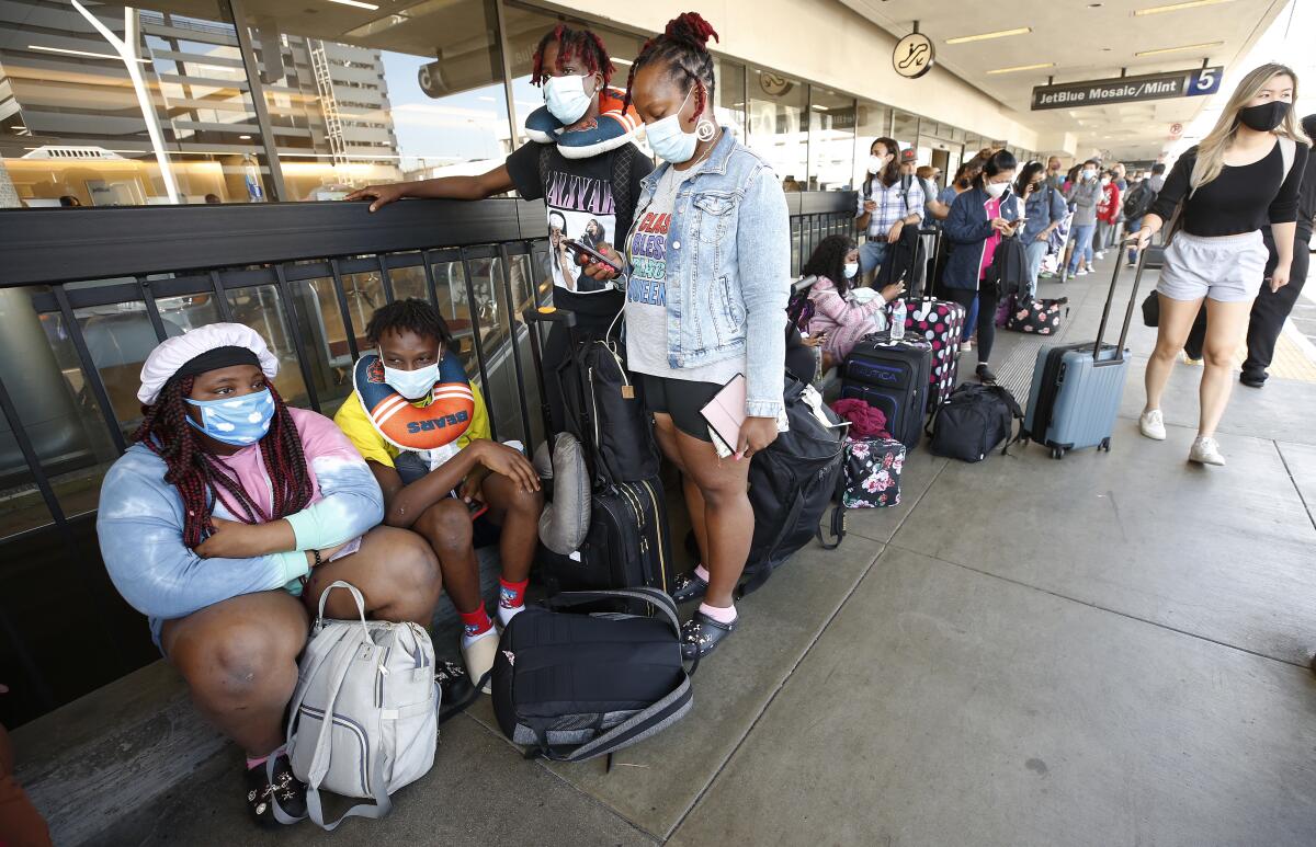 A family waits with their luggage for a flight to Chicago after it is canceled.