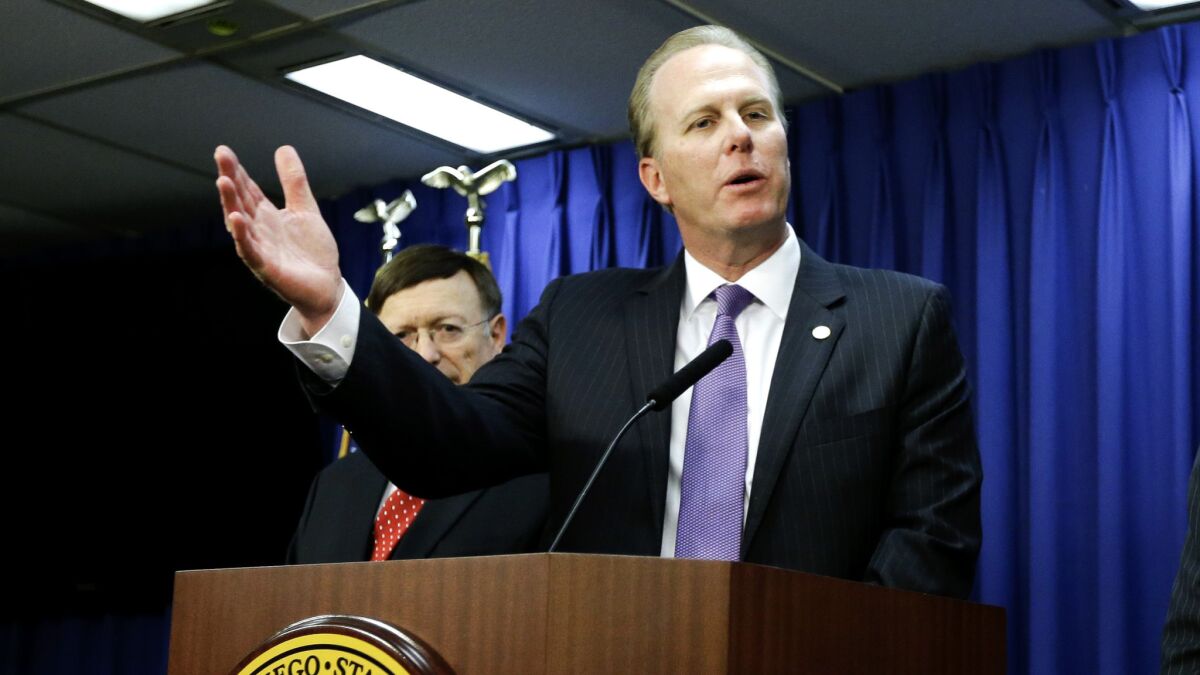 Kevin Faulconer, behind a podium, gestures as he speaks to reporters in 2016.