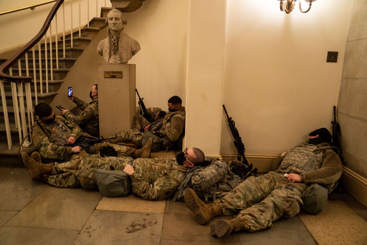 Guardsmen stretch out around a bust of Jefferson and a staircase.