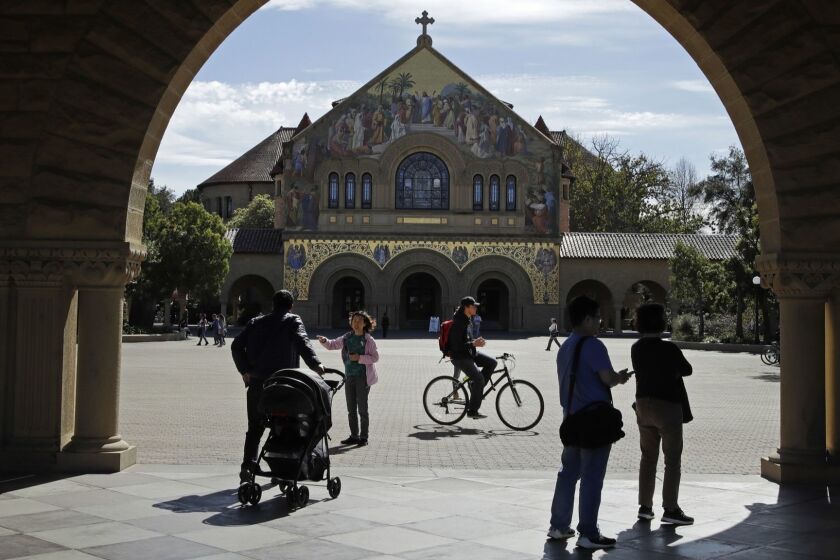 People walk near Memorial Church on the Stanford University campus Thursday, March 14, 2019, in Santa Clara, Calif. In the first lawsuit to come out of the college bribery scandal, several students are suing Yale, Georgetown, Stanford and other schools involved in the case, saying they and others were denied a fair shot at admission. The plaintiffs brought the class-action complaint Wednesday, March 13, 2019, in federal court in San Francisco on behalf of themselves and other applicants and asked for unspecified damages. (AP Photo/Ben Margot)