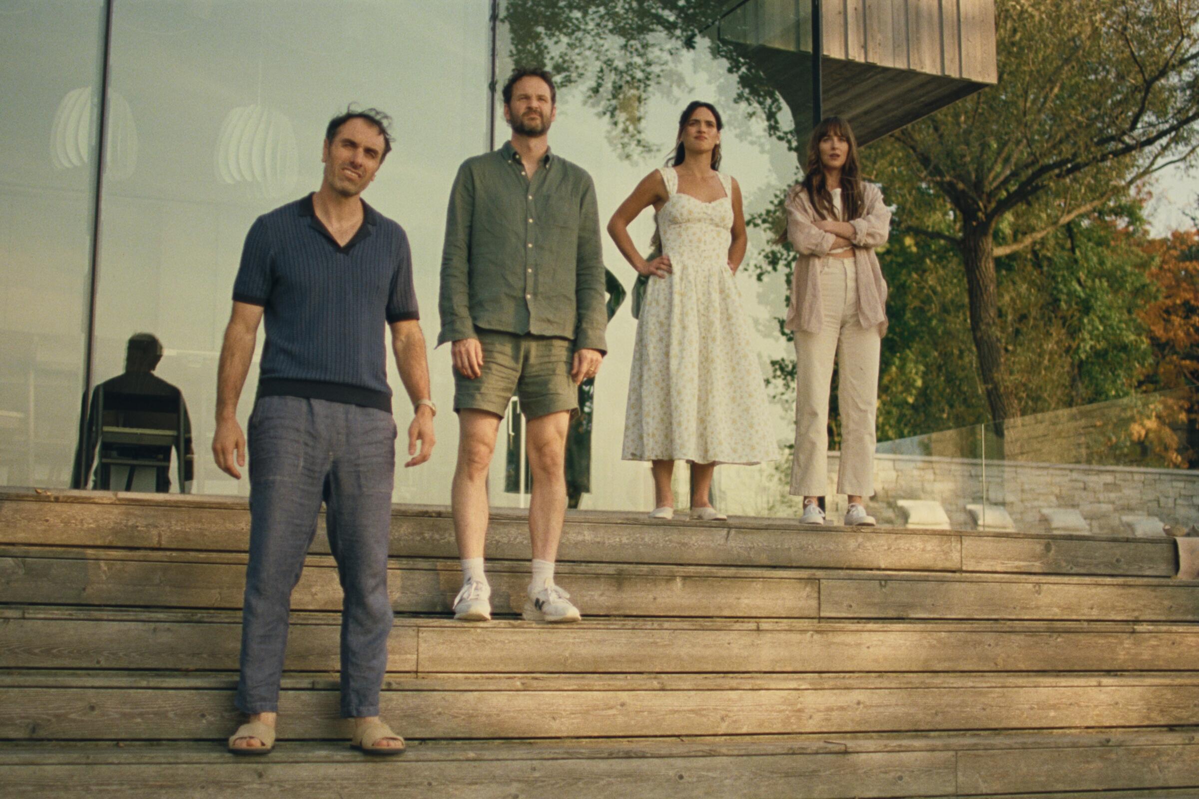 Four confused lovers stand on steps in front of a building.