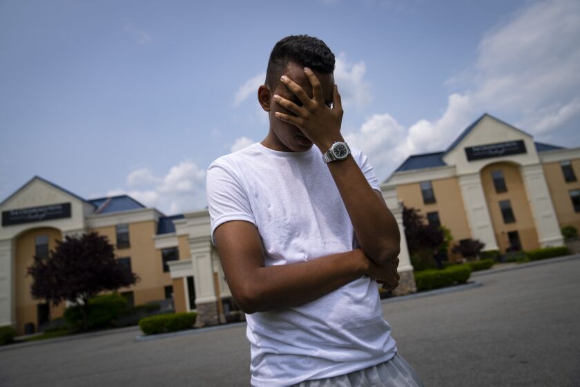 FILE - Mohamed, a 19-year-old fleeing political persecution in the northwest African country of Mauritania, poses for a photo that obscures his face to protect his identity, outside the Crossroads Hotel, before heading into town for a work opportunity, May 22, 2023, in Newburgh, N.Y., in Orange County. Mohamed is one of about 400 international migrants the city has been putting up in a small number of hotels in other parts of the state to relieve pressure on its overtaxed homeless shelter system. New York City sued nearly half the state's counties Wednesday, June 7, over their attempts to keep out international migrants, the latest escalation in an ongoing battle between city officials and local leaders. (AP Photo/John Minchillo, File)