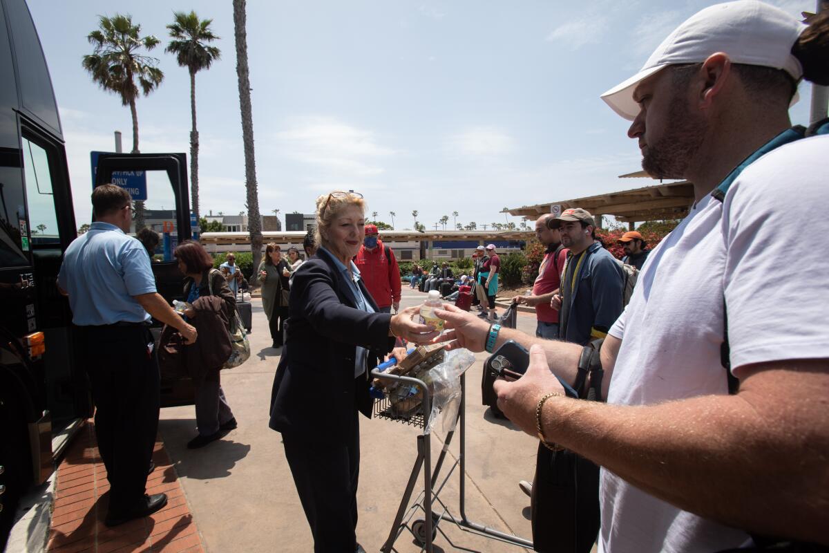 An Amtrak employee offers water to passengers who will be taking a bus to Irvine at the Oceanside Transportation Center