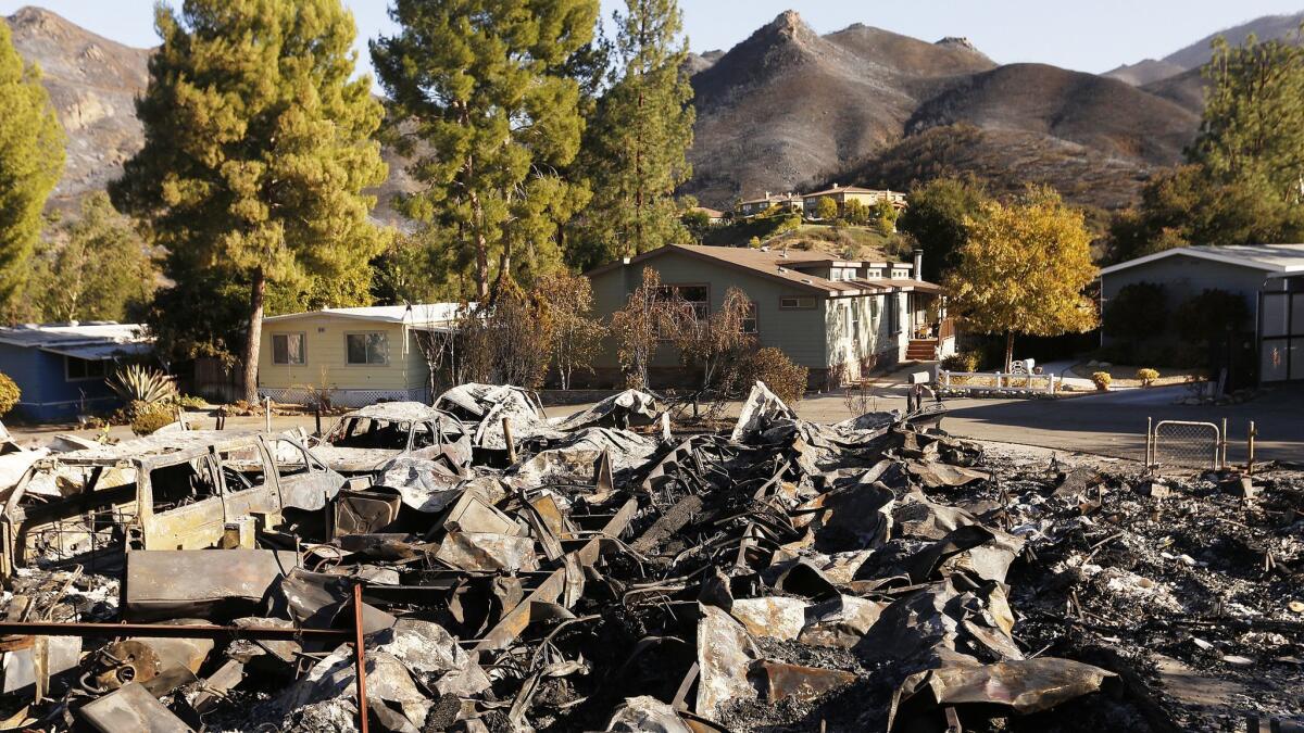 Some of the remaining homes in the Seminole Springs mobile home park stand behind ruins of those destroyed by the Woolsey Fire.