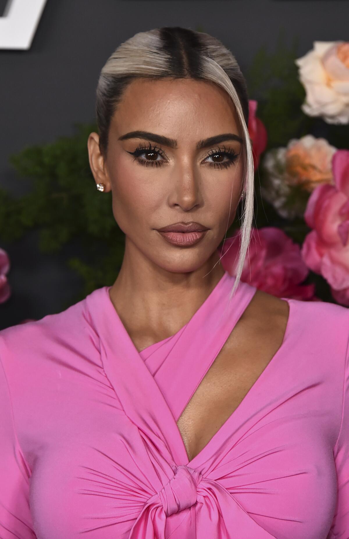 Kim Kardashian poses in a hot pink top with bleached streaks in her hair