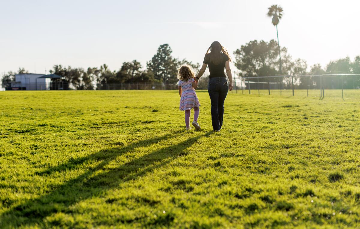 Alexia Carbone walks hand-in-hand with her 5-year-old transgender daughter "A." at a park near their home.