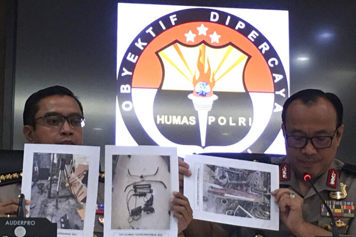 Dedi Prasetyo, right, national police spokesman in Indonesia, helps display photos of confiscated items during a news conference Oct. 17 in Jakarta.
