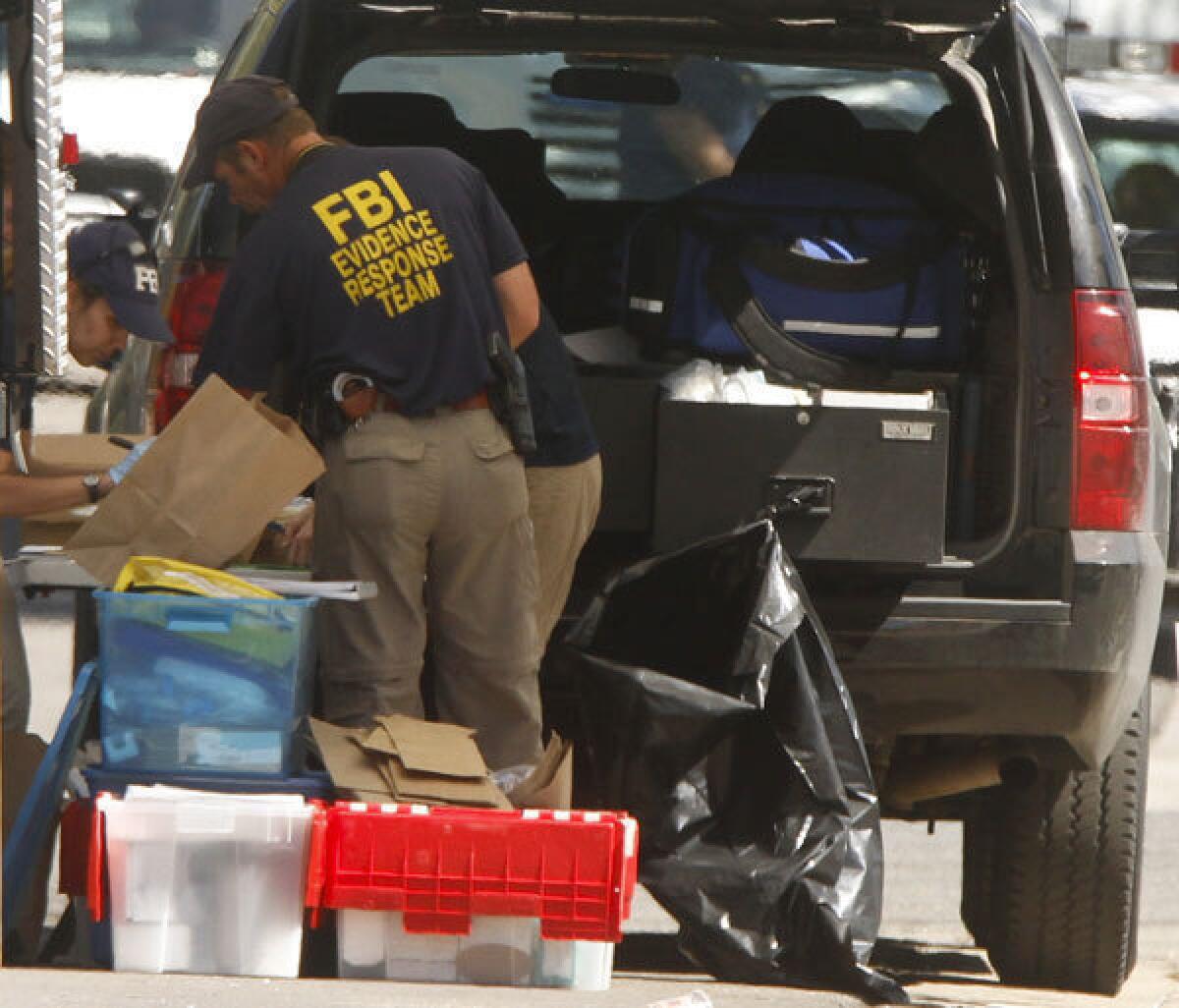 FBI investigators look over some of the items taken from suspect James Holmes' apartment in Aurora, Colo.