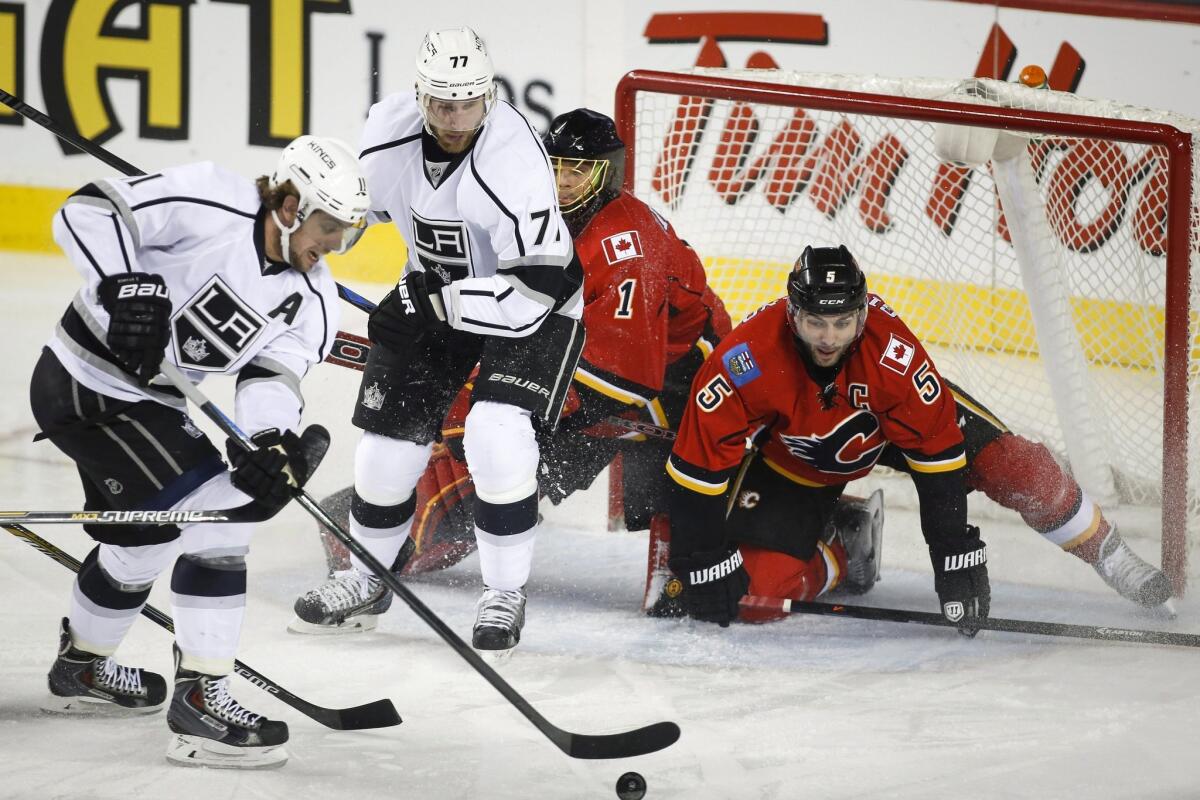 Kings players Anze Kopitar, left, and Jeff Carter try to score on Calgary goalie Jonas Hiller, second from right, who gets some help from teammate Mark Giordano.