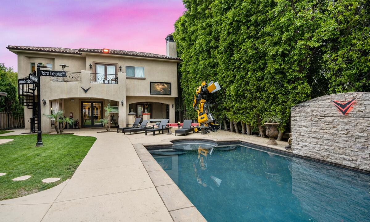 The Mediterranean-style property includes a backyard with a movie screen, pool, street sign and  Transformers replica.