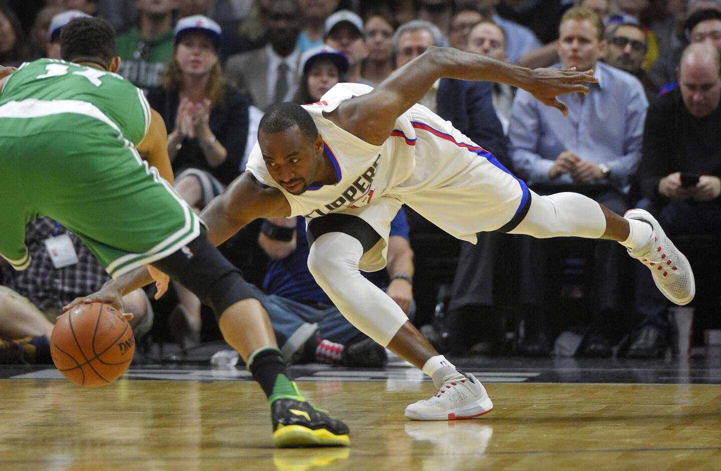 Clippers forward Luc Richard Mbah a Moute reaches for a loose ball along with Celtics guard Evan Turner during the first half.