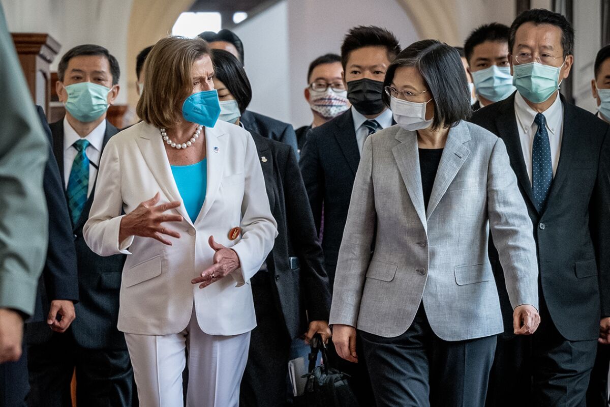 Two women in face masks lead a group of people walking.