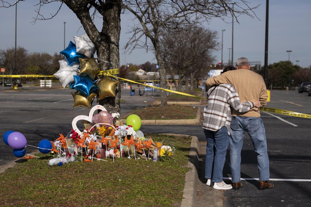 A couple embracing by a memorial to Walmart mass shooting victims in Chesapeake, Va.