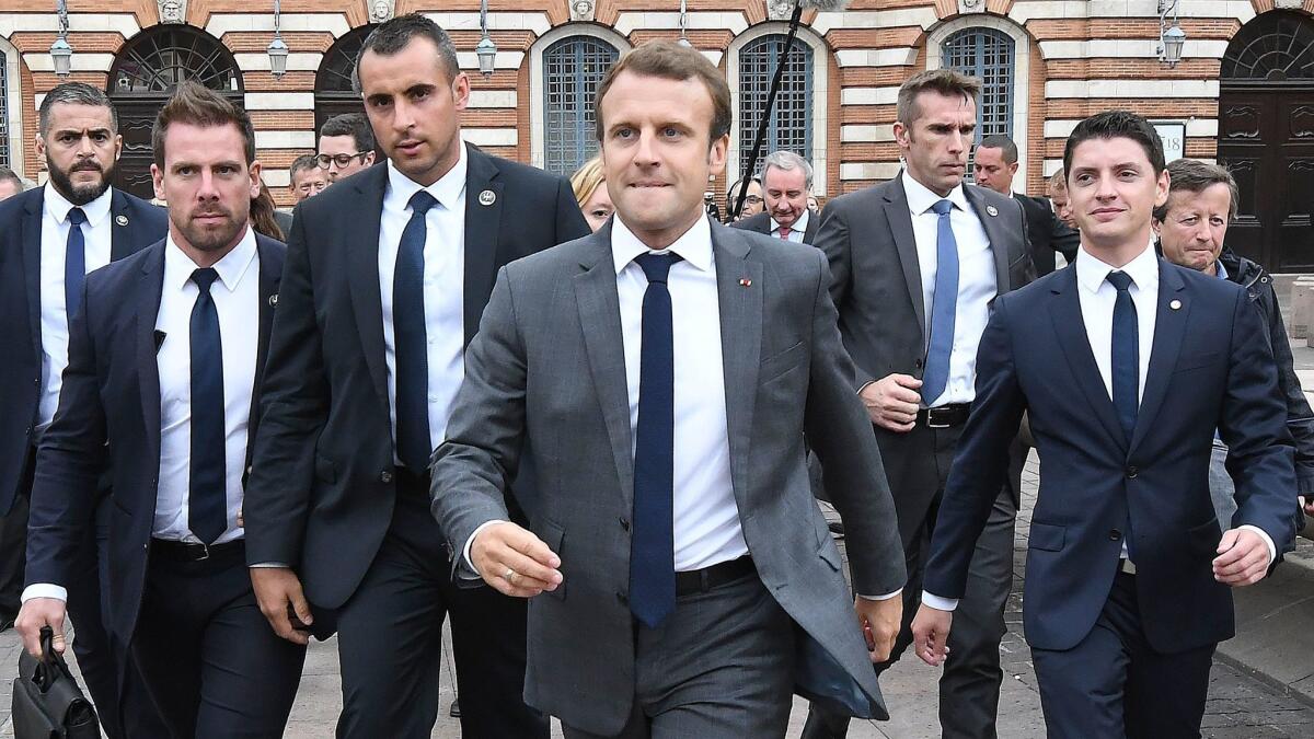French President Emmanuel Macron, center, walks surrounded by members of the presidential security service at the Place du Capitole in Toulouse, southern France, before attending a round table on Monday.