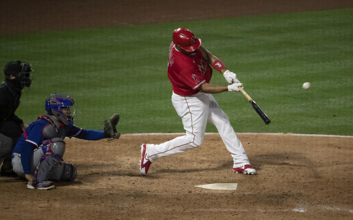 Angels' Albert Pujols hits a solo home run as Texas Rangers catcher Jose Trevino watches.