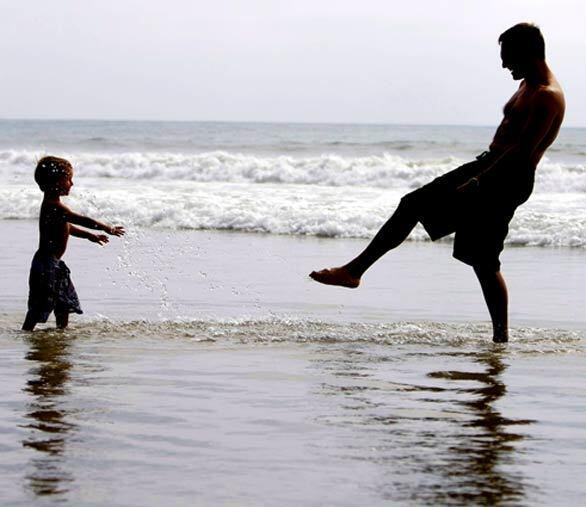 Oliver Devanneaux of San Diego plays in the surf with his son, Eloi, 2, at San Elijo State Campground in Cardiff-by-the-Sea.