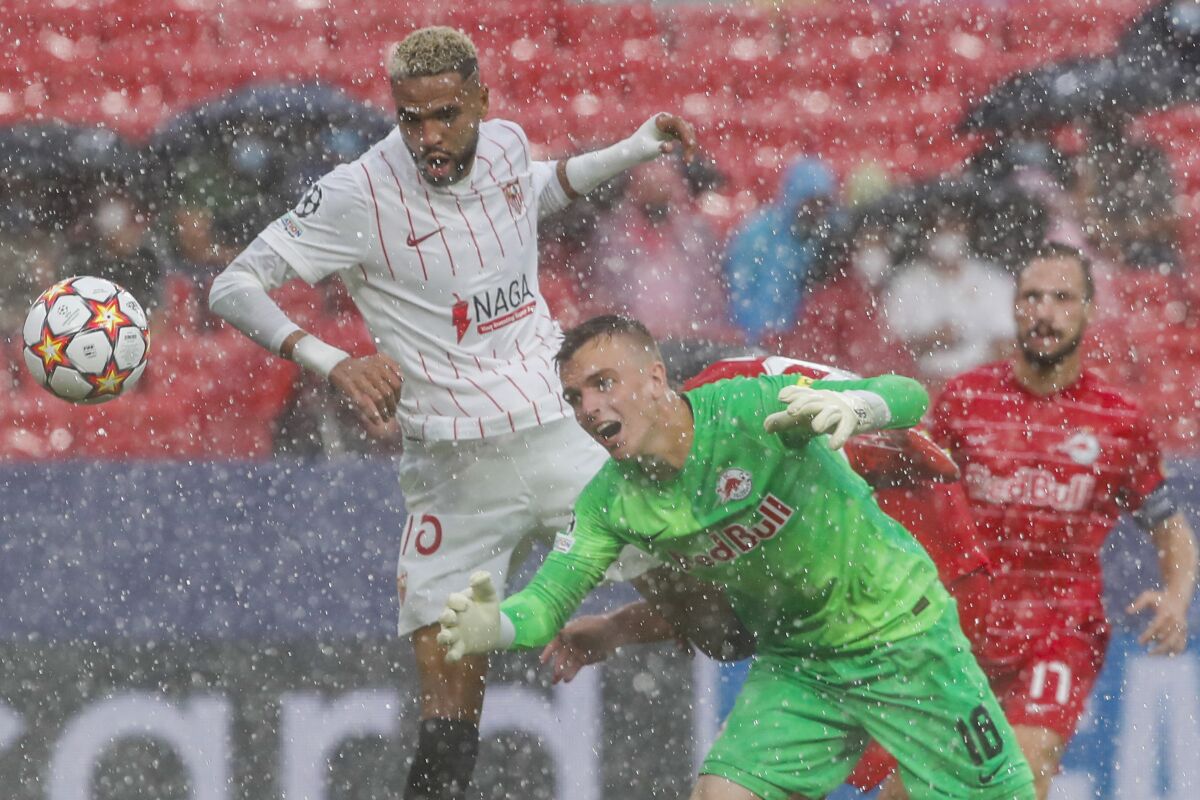 Salzburg's goalkeeper Philipp Koehn, right, tries to save a ball next to Sevilla's Youssef En-Nesyri during the Champions League, Group G soccer match between Sevilla and Salzburg at the Ramon Sanchez Pizjuan stadium in Seville, Spain, Tuesday, Sept. 14, 2021. (AP Photo/Angel Fernandez)