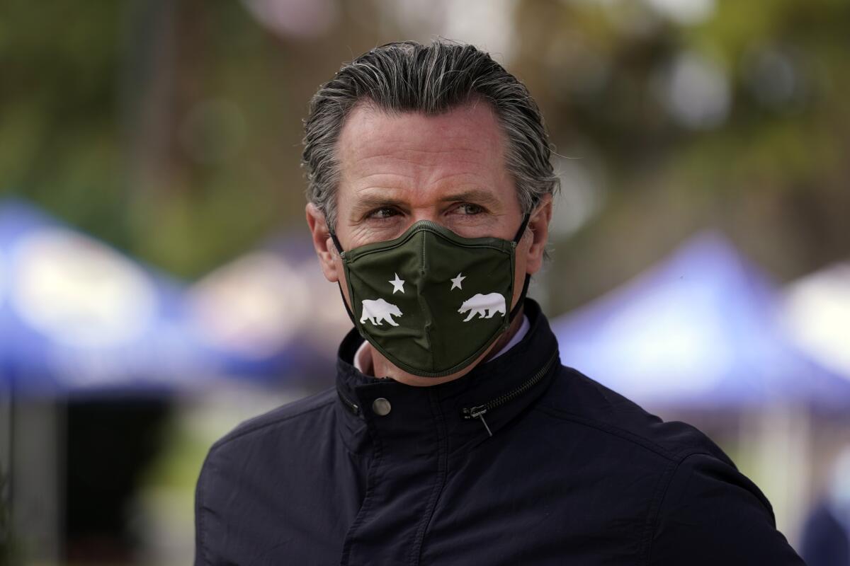 A closeup of Gavin Newsom in a mask with California flag insignia.