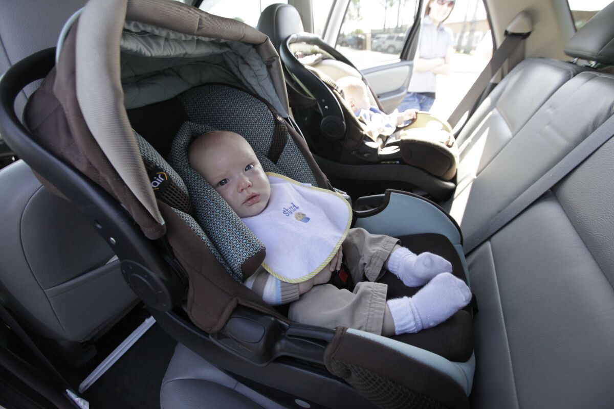 An infant sits in a rear-facing car seat