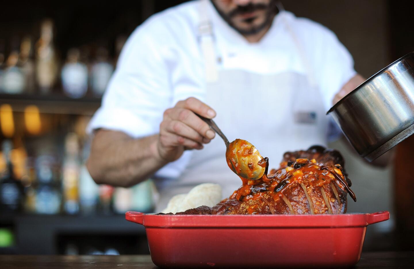 Chef Francis Derby pours the sauce for General Tso pig's head at the Cannibal.