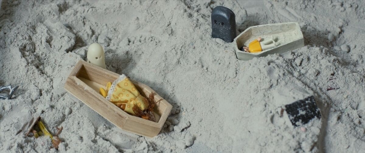 Toy figures and caskets in sand from the documentary "Beautiful Something Left Behind."