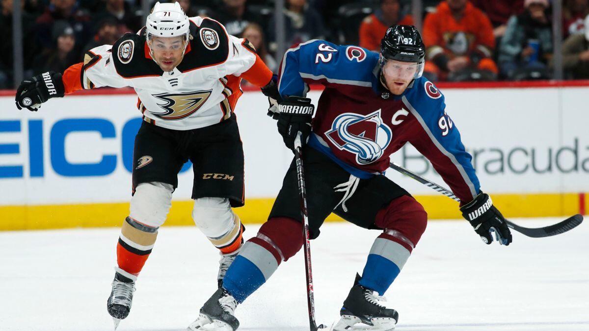Colorado Avalanche left wing Gabriel Landeskog, right, picks up a loose puck in front of Ducks right wing J.T. Brown in the first period Monday.