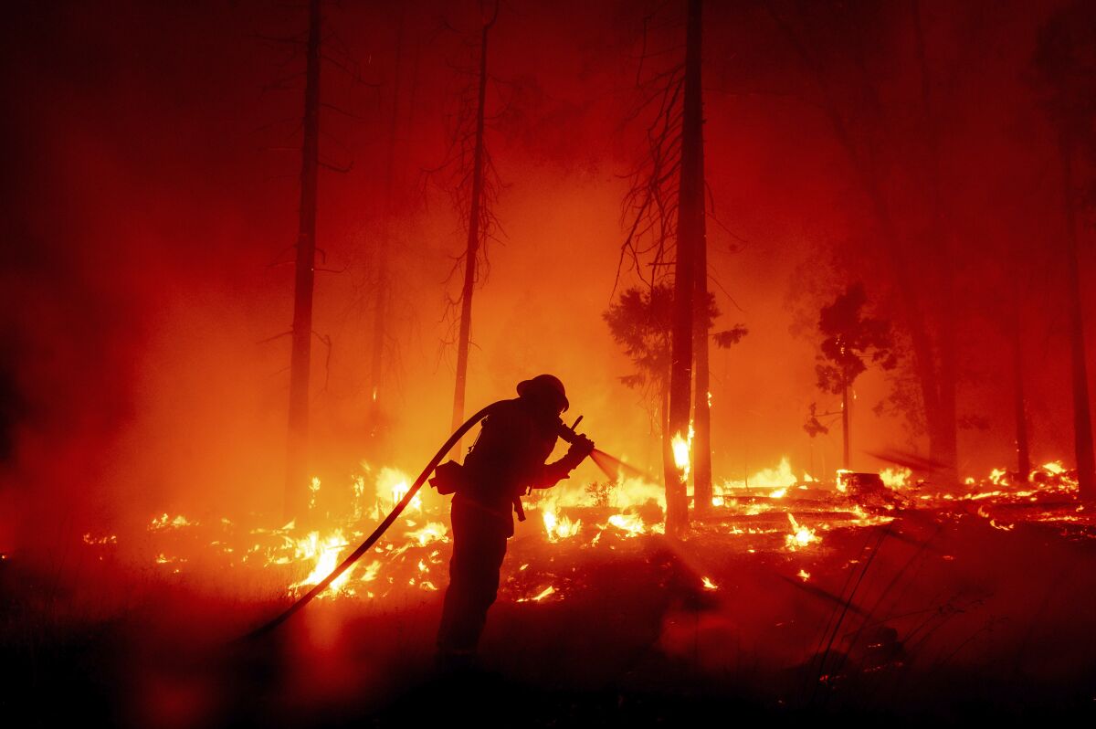 A firefighter battles the Creek Fire as it threatens homes in the Cascadel Woods neighborhood of Madera County, Calif.