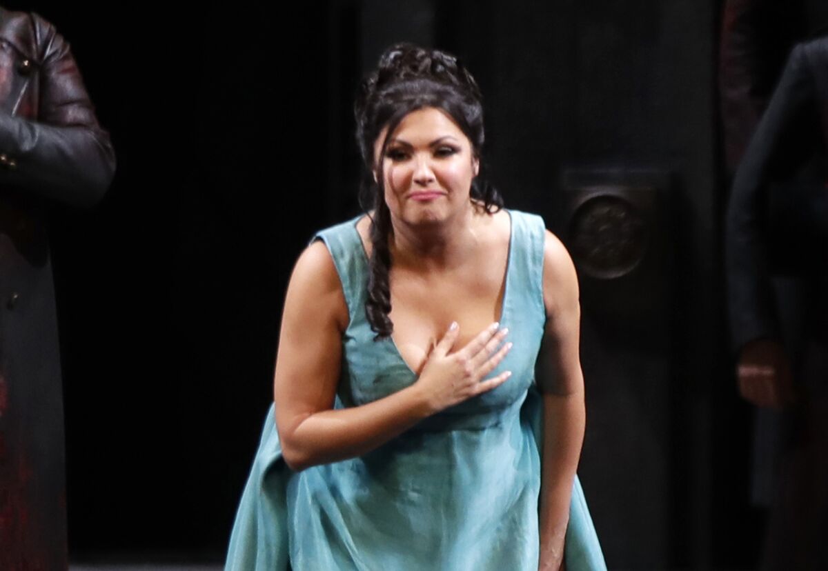 A female opera singer in a blue gown takes a bow