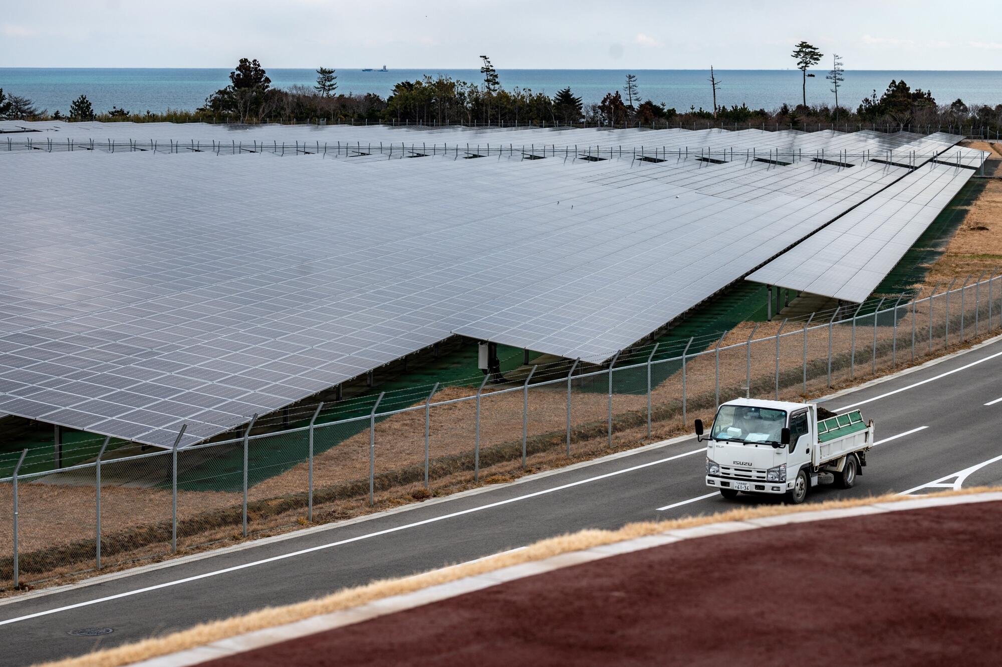 A truck drives past solar panels in Japan.