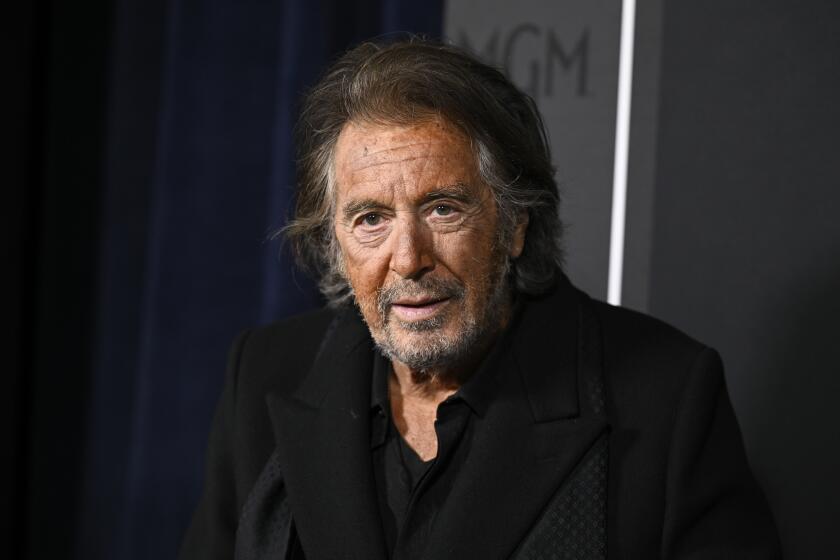 Al Pacino with facial hair wearing a dark suit and dark shirt looking straight ahead