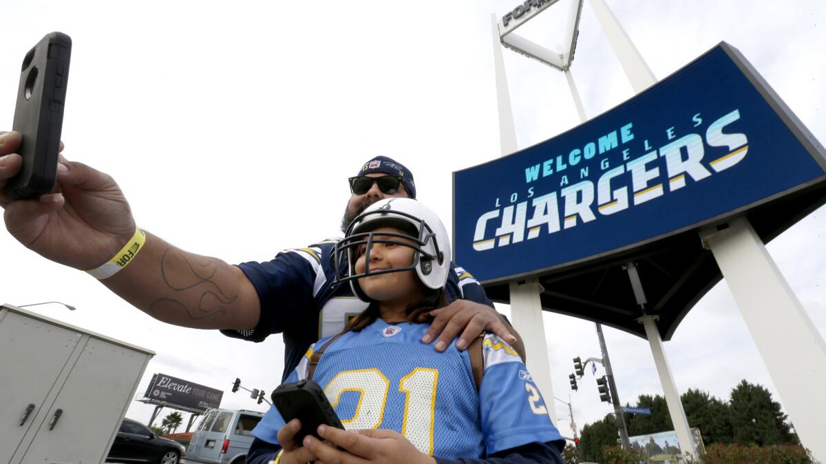 Chargers fans Luis Salas and his daughter Lily Salas, 9, take a selfie in front of a "Welcome Los Angeles Chargers," sign at The Forum on Jan. 18.