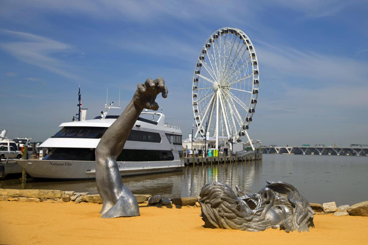 The new Capital Wheel rises above National Harbor, and the sculpture "The Awakening," foreground, outside Washington, D.C.