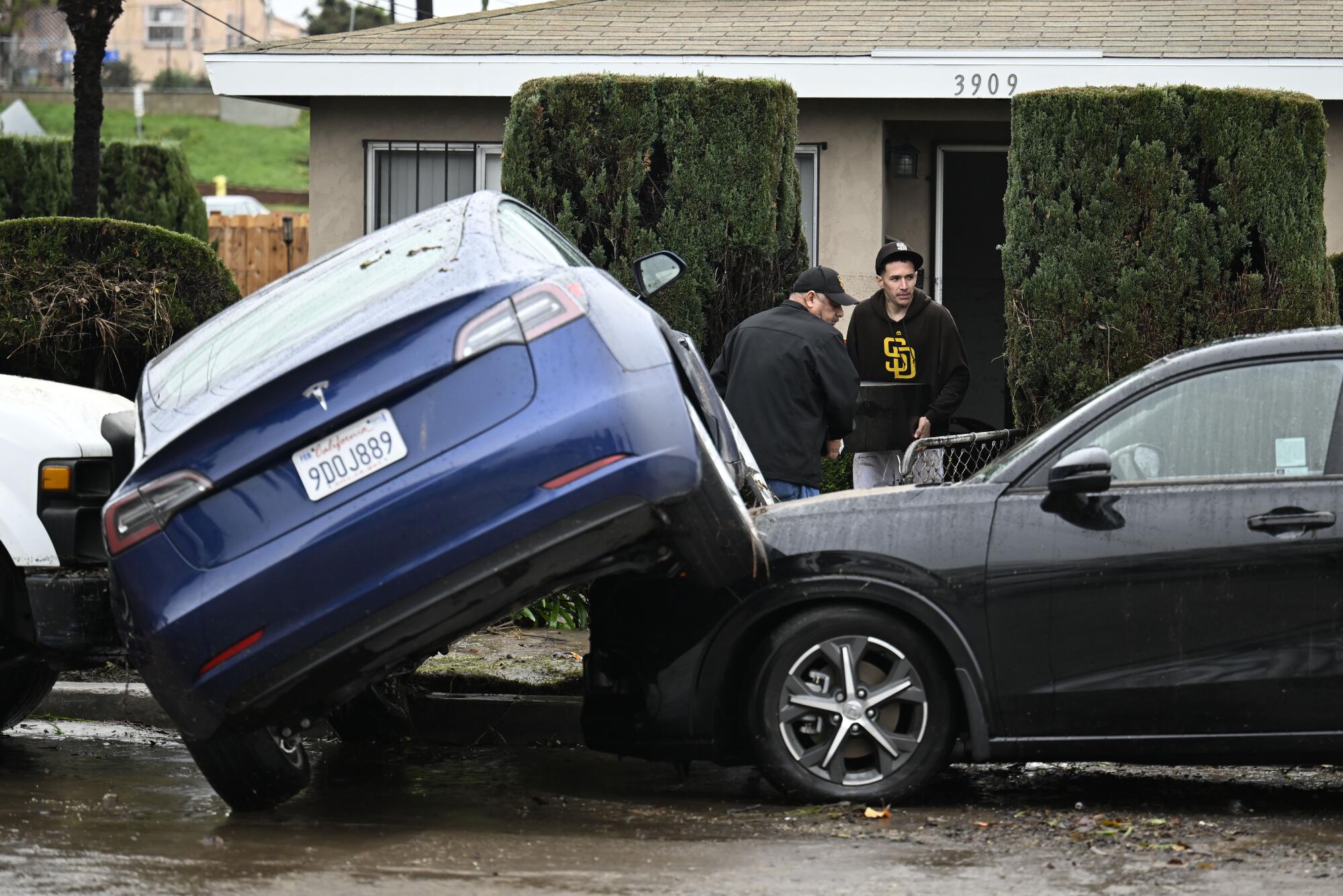 Residents move furniture from a home damaged by flooding next to cars moved by the waters during a rainstorm in San Diego.