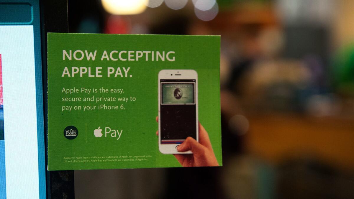 Apple Pay is promoted on signs placed at the cash register of a Whole Foods in New York. Apple's stock price rose after an analyst cited growth of its services businesses such as music and payments.