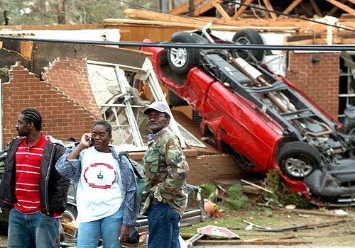 Residents gather near an overturned truck which landed against a house in Enterprise, Ala., Thursday, March 1, 2007. An apparent tornado struck the high school, trapping students under rubble and killing at least eight people, emergency officials said. More than 40 people were brought to an Enterprise hospital, and damaged homes and one death were reported in west Alabama as a violent storm front crossed the state.
