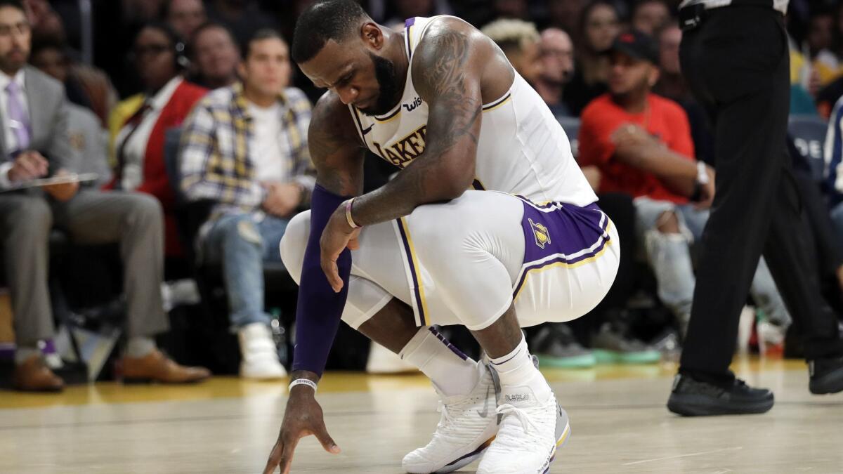 Lakers' LeBron James kneels after a foul is called against the Lakers during the second half against the Toronto Raptors on Sunday.