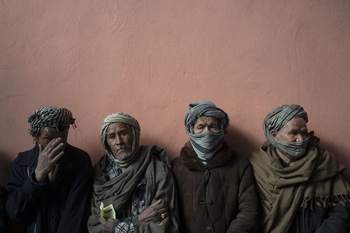 Men wait in a line to receive cash at a money distribution organized by the World Food Program (WFP) in Kabul, Afghanistan, Wednesday, Nov. 3, 2021. Afghanistan's economy is fast approaching the brink and is faced with harrowing predictions of growing poverty and hunger. (AP Photo/Bram Janssen)