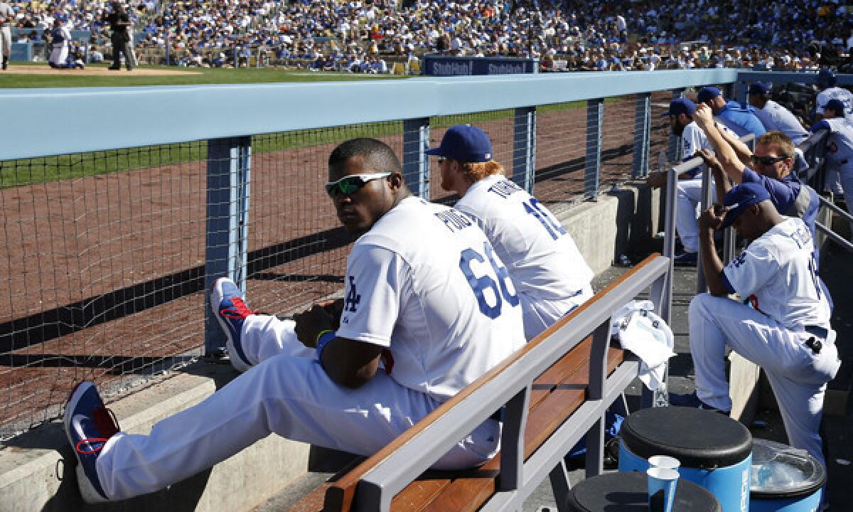 Dodgers outfielder Yasiel Puig watches Friday's home opener against the San Francisco Giants from the dugout after he was benched by Manager Don Mattingly for arriving late to the ballpark.