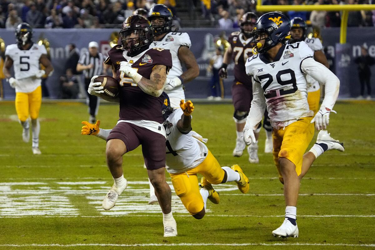 Minnesota running back Ky Thomas runs away from West Virginia safety Alonzo Addae and safety Sean Mahone.