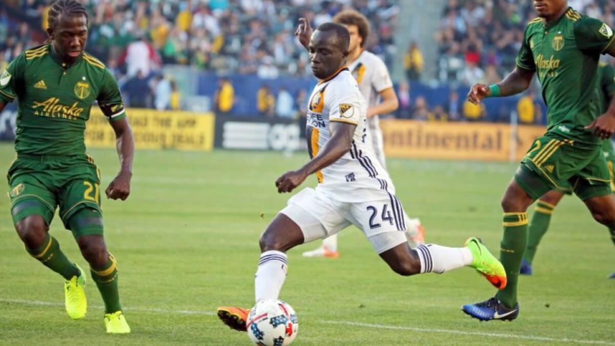 Galaxy midfielder Emmanuel Boateng drives the ball against Timbers defenders Diego Chara (21) and Alvas Powell (2) during a game on March 12.