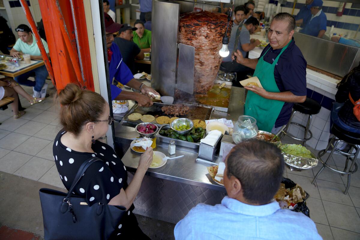 In Tijuana, Mexico, customers are encouraged to sit next to the tacos al pastor grill and order directly from Juan Manuel de Estrada.