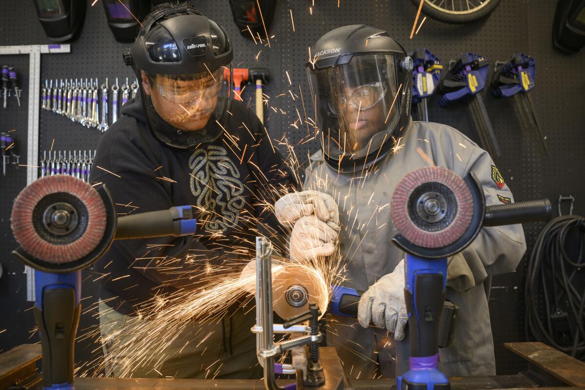 Instructor Carlos Alonzo, left, shows Miracle Chaney, 17, left, how to cut steel with a grinder.